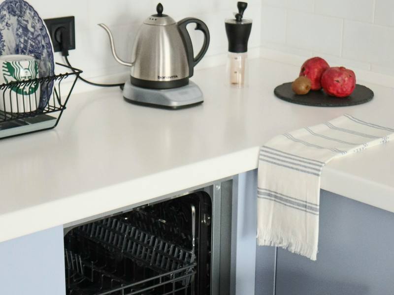 Open built-in dishwasher beneath a kitchen counter